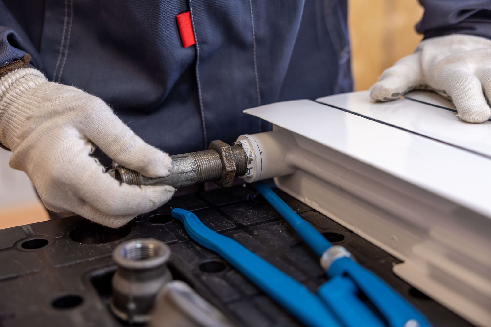Sample image of gloved hands fitting a pipe to a radiator